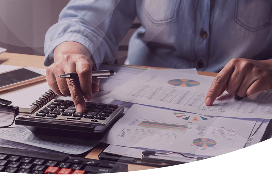 Business person calculating finances with calculator and pointing at graph